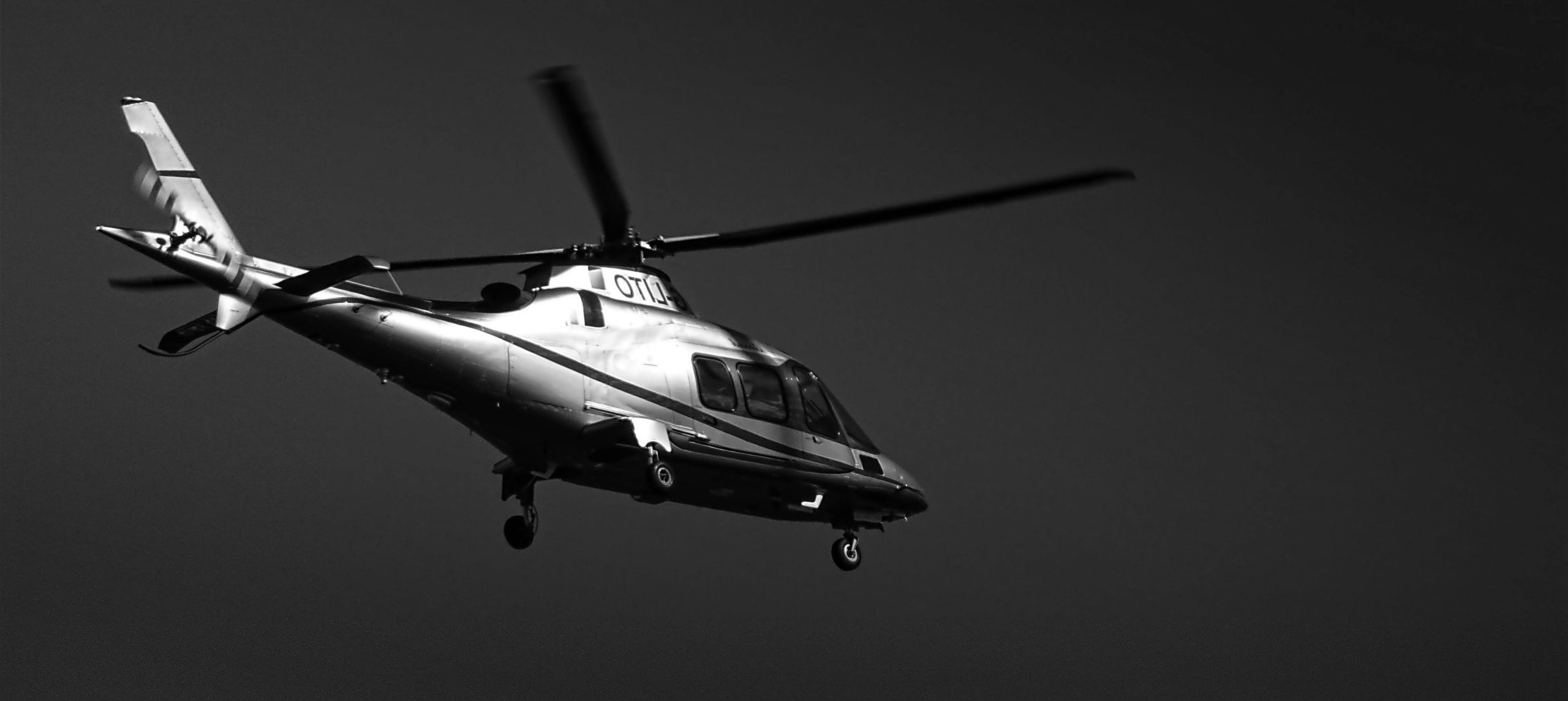 Black and white image of a helicopter flying with clear detailing.